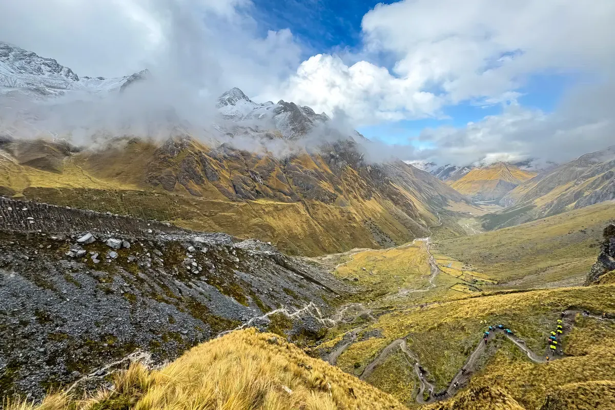 Trekkers on the switchbacks below the Salkantay Pass, with the glacier peaks in cloud, on a Salkantay trek tour